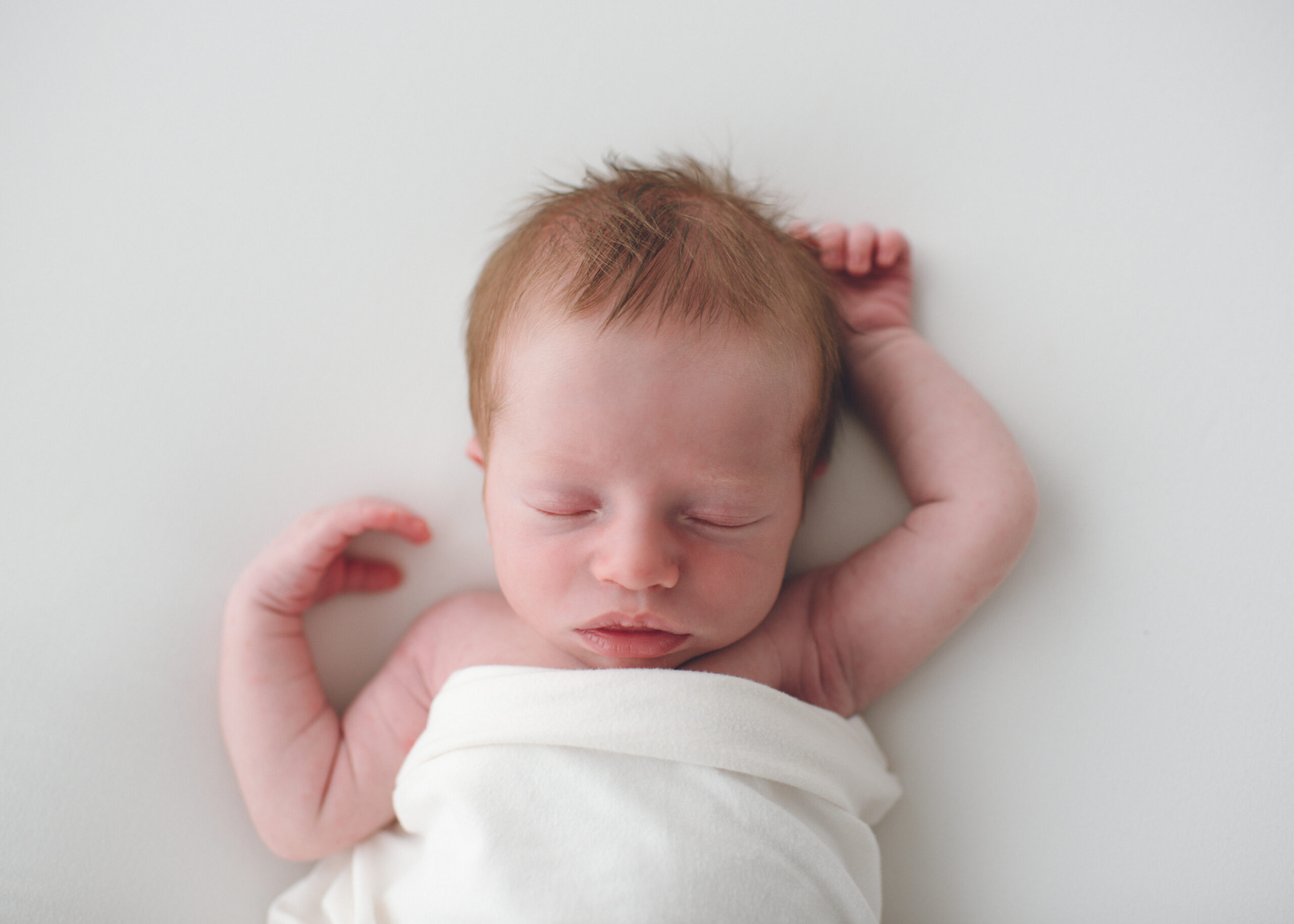 Simple newborn baby photo on white blanket in studio